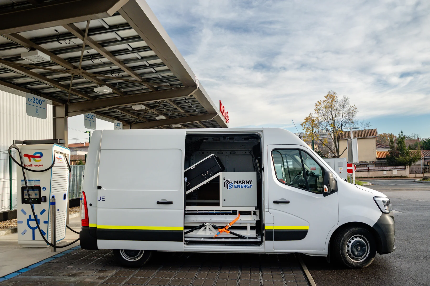 Marny Energy storage built into a white Renault Master van, side door open, charging at a DC fast-charging station